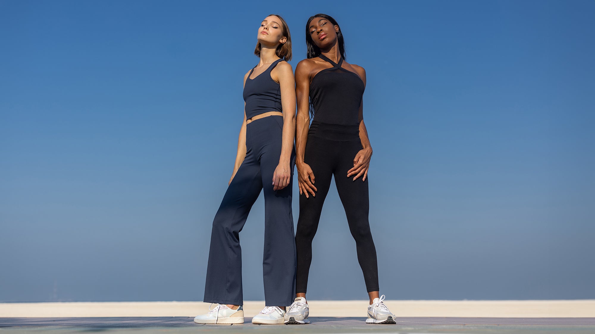 2 Frauen in Sport-Outfits vor blauem Himmel